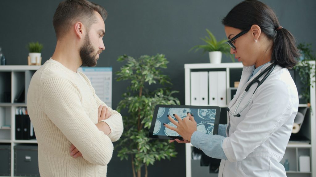 Dwie osoby, z których jedna jest lekarzem – patrzą na tablet, który trzyma w ręku lekarz